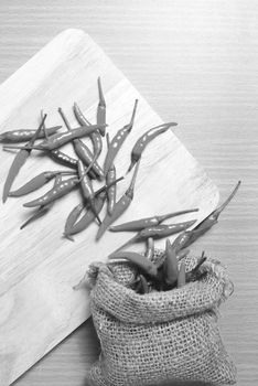 red chili peppers on cutting board over wood table background black and white tone color style