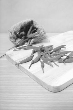 red chili peppers on cutting board over wood table background black and white tone color style