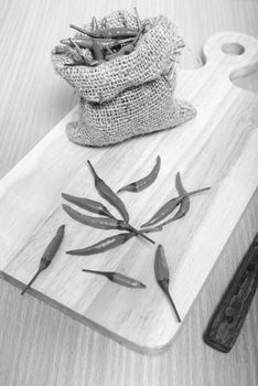 red chili peppers on cutting board over wood table background black and white tone color style