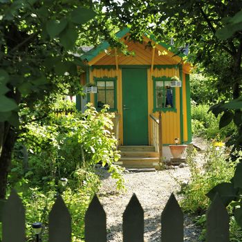 Small yellow cottage by a green summer meadow.