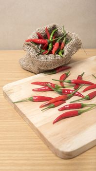 red chili peppers on cutting board over wood table background