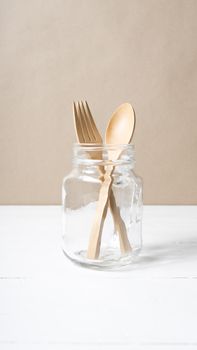 wood spoon and fork with glass over white table