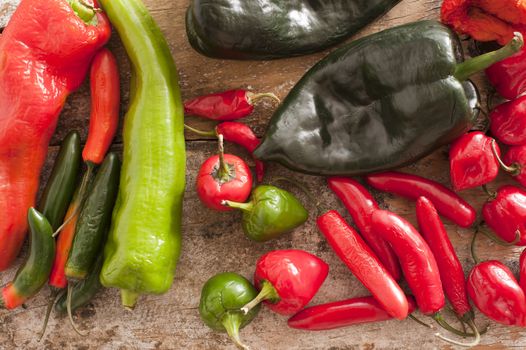 High Angle View of Assorted Red and Green Chili Peppers on a Rustic Wooden Table.