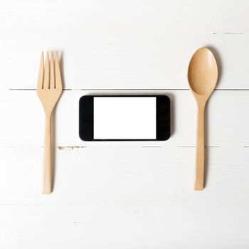 spoon and smart phone concept eating social over white table background