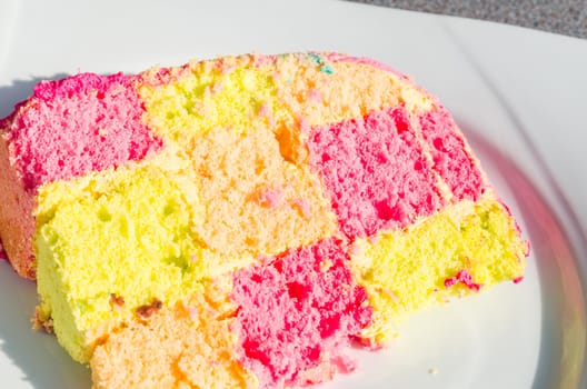Clorful checkered birthday cake. Cake on white plate.