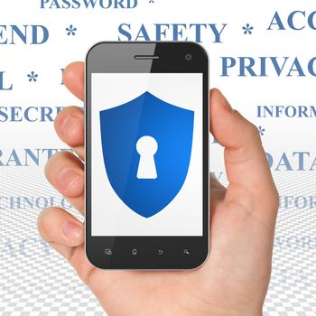 Protection concept: Hand Holding Smartphone with  blue Shield With Keyhole icon on display,  Tag Cloud background