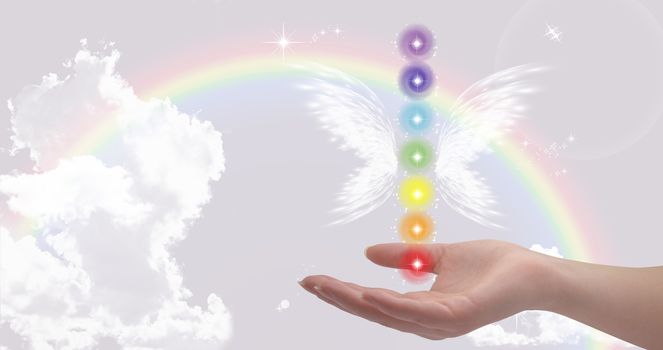 Healing hand and seven chakras on a sky background with rainbow