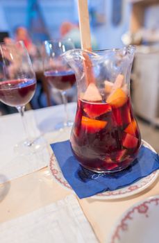 Large jar of sangria with red wine, oranges and ice served in a restaurant.