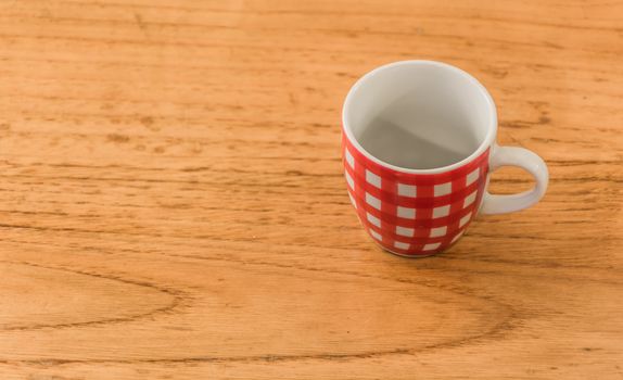 an empty red and white striped coffee cup over a wooden table