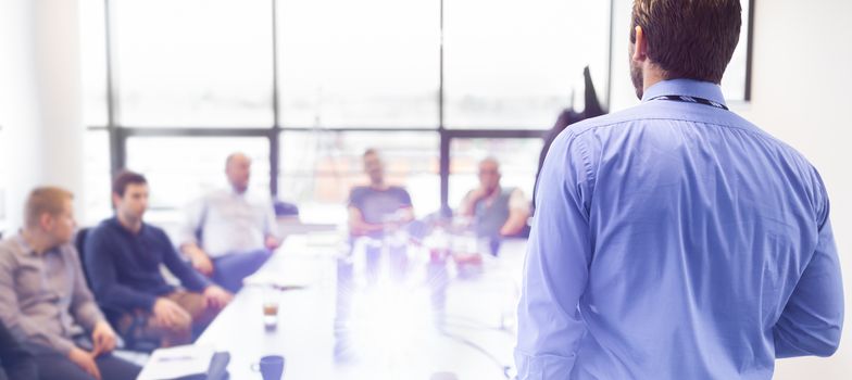 Business man making a presentation at office. Business executive delivering a presentation to his colleagues during meeting or in-house business training, explaining business plans to his employees. 