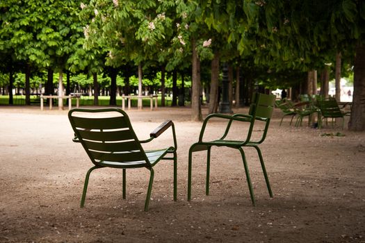 Two green emty chairs standing in a park