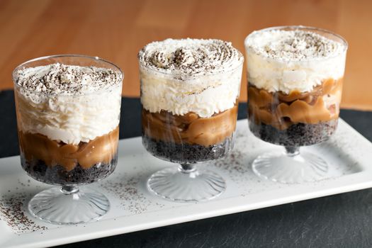 Banana caramel parfait desserts with fresh whipped cream and chocolate cookie crumbles. Shallow depth of field.