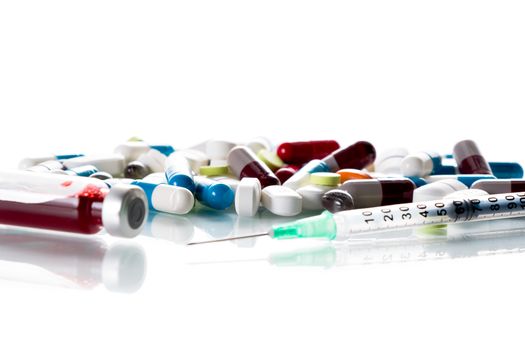 Tablets and a syringe lying on a white table