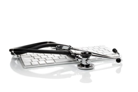 Black stethoscope lying on computer keyboard