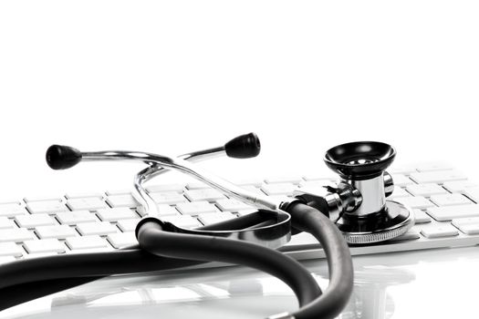 Black stethoscope lying on computer keyboard