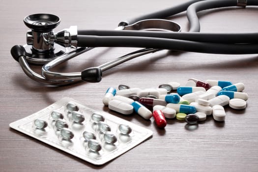 A Sthetoskop and medicines are on a brown desk