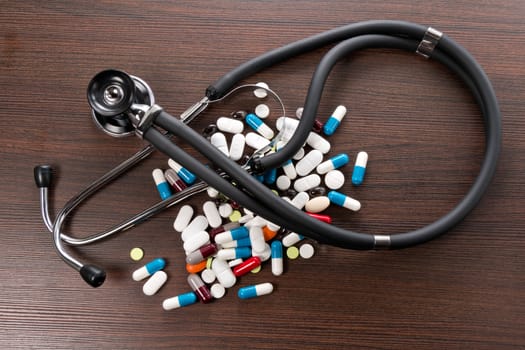 A Sthetoskop and medicines are on a brown desk