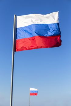 Russian flag, growing in the wind with blue sky as background