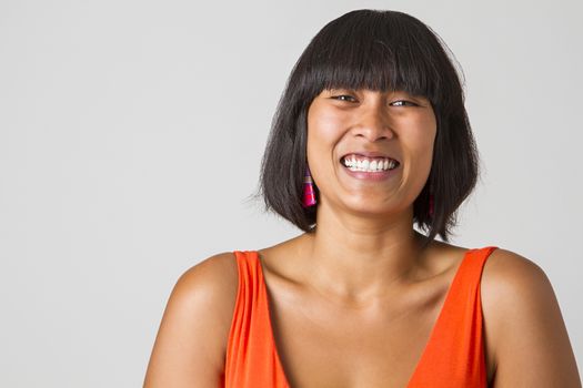 Asian girl laughing hard against a white background