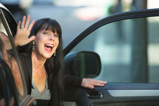 Attractive woman waving as she exits vehicle on downtown street