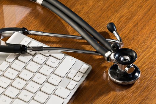 Black stethoscope lying on computer keyboard