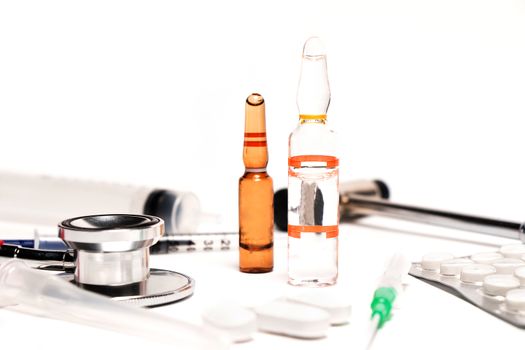 Tablets and a syringe lying on a white table