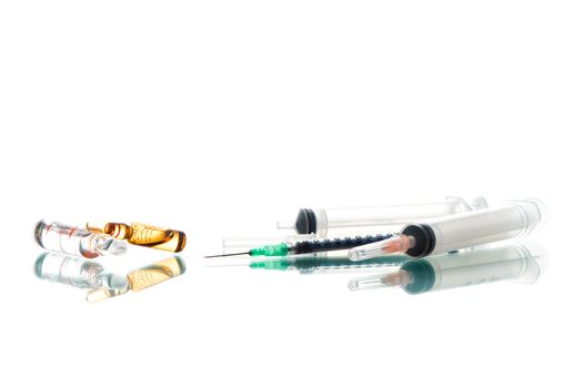 Tablets and a syringe lying on a white table