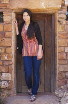 Biracial teen girl standing in low,  brick doorway of home, leaning against doorframe