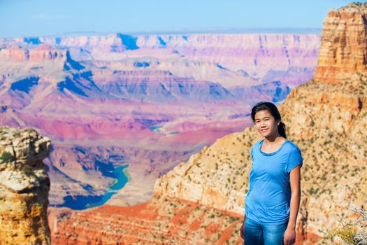 Young teen girl standing at the Grand Canyon, Arizona, in front of colorful canyon walls 