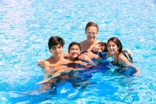 Multiracial family swimming together in pool. Disabled youngest son has cerebral palsy.