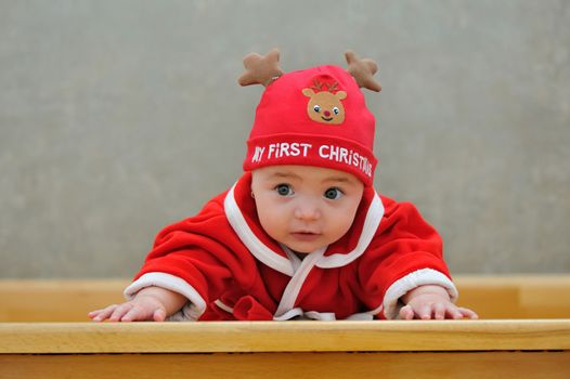A baby in a Santa suit on stairs