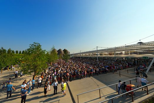 MILAN, ITALY - AUGUST 31, 2015: Long queue of visitors waiting in the morning at entrance of Expo Milano 2015, universal exposition on the theme of food, in Milan, Lombardy, Italy, Europe