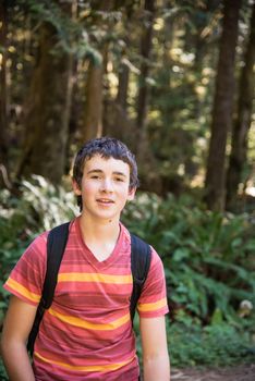 13 year old boy with backpack hiking in forest