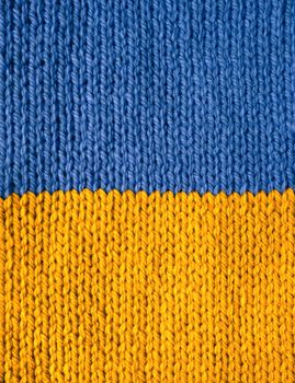 Stockinette stitch knitting in blue and yellow wool as an abstract background texture