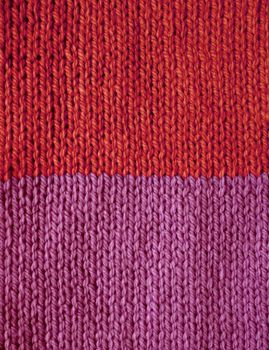 Red and purple striped stocking stitch knitting as an abstract background texture