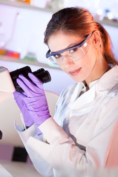 Life scientist researching in laboratory. Portrait of a attractive, young, confident female health care professional microscoping in hes working environment. Healthcare and biotechnology.