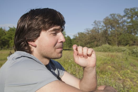 Young man sitting in a meadow on a sunny day