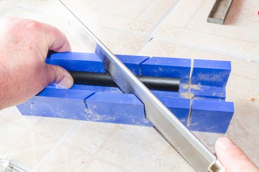 Hand of a worker with miter saw against a bright background.