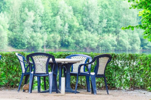 Simple blue plastic chairs and table on a terrace overlooking the lake.