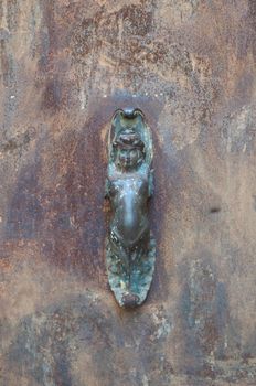 Old iron handle shaped like a woman stuck in an old port that is used to knock