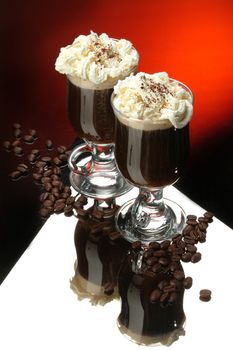 Two glasses of coffee and cream on a glass background
