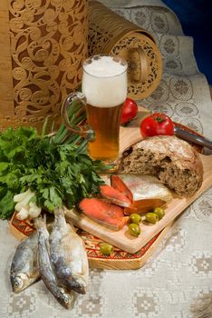 Glass of beer, piece of bread and fish on a tablecloth