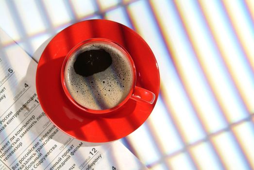 Red cup of coffee and a part of newspaper