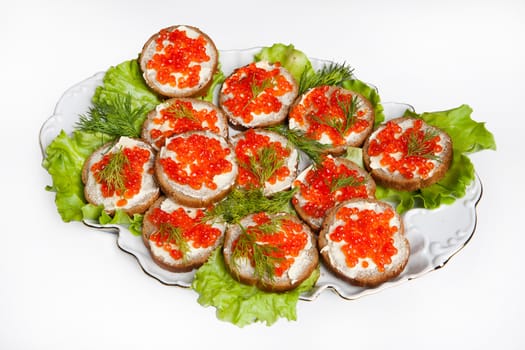 Plate with little sandwiches with red caviar and vegetables