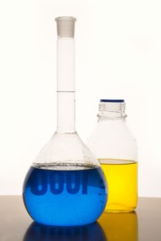 Measuring glasses on a table with blue and yellow liquid of a chemical laboratory