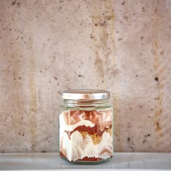 Homemade cheesecake in a glass jar on gray background