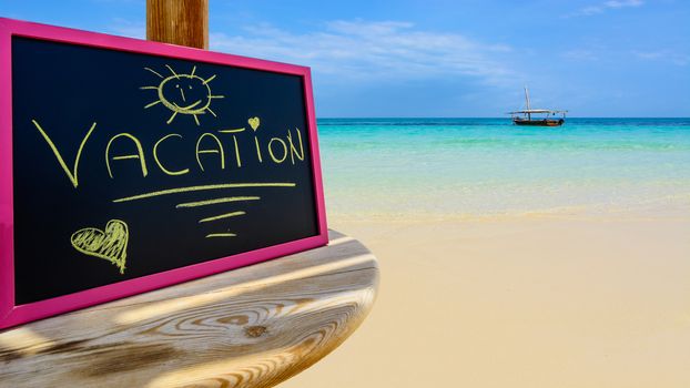 In the picture a Zanzibar beach which is a small blackboard with the words " Vacation" in the afternoon .