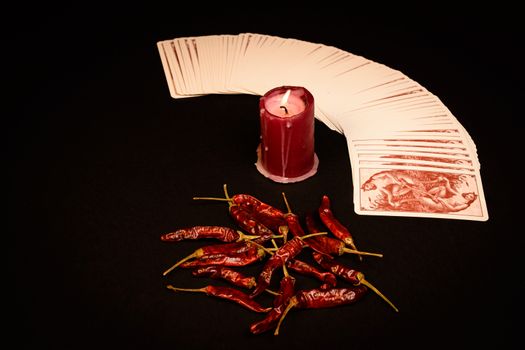 In the pictured a deck of cards open fan , a red candle and red pepper dry.