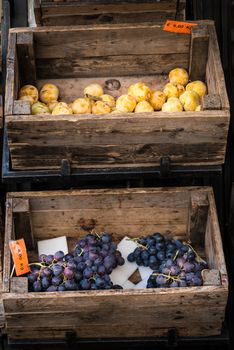 In the photo two old wooden boxes with inside the fruit (grapes and plums)