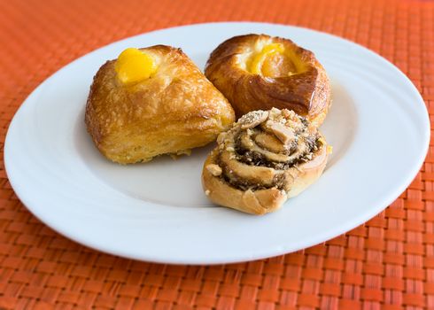 In the pictured three pastries served on a white plate .